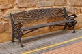 A metal bench against the wall lined with stone Royalty Free Stock Photo