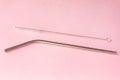 Metal, bendy drinking straw and steel cleaning brush on pink background. Aluminum stainless reusable bar equipment for drink