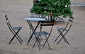 Metal black chairs and tables in a cafe on a cobbled square. everything is made of light material that can be folded and cleaned e Royalty Free Stock Photo