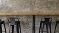 Metal black high chair with wooden table and concrete style wall in cafe Royalty Free Stock Photo