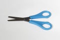 Metal and blue plastic scissors layed on white surface