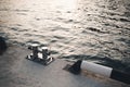 Metal bollard for boats and vessels on wharf over sea and sunset background close up.