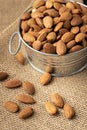 Metal bowl full of almonds on a sackcloth. Pile of nuts stacked together randomly on the burlap background. Healthy nutrition Royalty Free Stock Photo