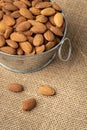 Metal bowl full of almonds on a sackcloth. Pile of nuts stacked together randomly on the burlap background. Healthy nutrition Royalty Free Stock Photo