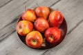 Metal bowl full of red ripe apples placed on gray wooden desk. Royalty Free Stock Photo