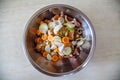 A metal bowl with raw sliced meat, pickled with spices, and vegetables for further cooking.