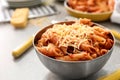 Metal bowl of tasty penne pasta with tomato sauce and grated cheese on table Royalty Free Stock Photo