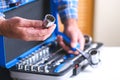 Metal box with a set of keys. A locksmith in a checked shirt holds a key attachment in his hand.