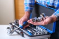 Metal box with a set of keys. A locksmith in a checked shirt holds a key attachment in his hand.