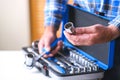 Metal box with a set of keys. A locksmith in a checked shirt holds a key attachment in his hand.