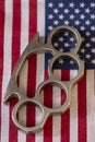 A metal brass knuckles lies against the background of the American flag. Concept: prohibited and permitted use of cold weapons, cr Royalty Free Stock Photo