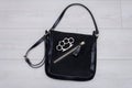 A metal brass knuckles is lying on a black woman`s handbag on a light background. Concept: women`s self-defense, bodily injury, qu