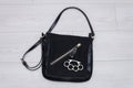 A metal brass knuckles is lying on a black woman`s handbag on a light background. Concept: women`s self-defense, bodily injury, qu