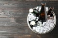 Metal bucket with bottles of beer and ice cubes on wooden background, top view. Space for text Royalty Free Stock Photo