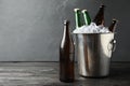 Metal bucket with bottles of beer and ice cubes on wooden table. Space for text Royalty Free Stock Photo