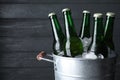 Metal bucket with bottles of beer and ice cubes on dark wooden background, closeup. Space for text Royalty Free Stock Photo