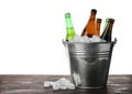 Metal bucket with bottles of beer and ice cubes on table against white background. Space for text Royalty Free Stock Photo