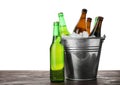 Metal bucket with bottles of beer and ice cubes on table against white background. Space for text Royalty Free Stock Photo