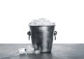 Metal bucket with ice cubes on table against background Royalty Free Stock Photo