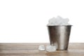 Metal bucket with ice cubes on wooden table against background Royalty Free Stock Photo