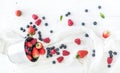 Metal bucket, strawberries, raspberries, blueberries and mint leaves, white wooden background