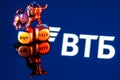 Metal bull stands on buy-sell dices on background of VTB bank logo