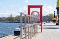 Metal buoy construction, lifebuoy in red wooden frame between sea and pavement Royalty Free Stock Photo