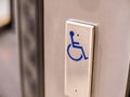 A metal button with a blue wheelchair symbol on it, object closeup, nobody. Accessibility for the disabled, building architectural Royalty Free Stock Photo