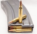 A metal 223 caliber rifle magazine loaded with 223 caliber bullets with two bullets on top of it Royalty Free Stock Photo