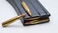 A metal 223 caliber rifle magazine loaded with 223 caliber bullets with two bullets on top of it Royalty Free Stock Photo