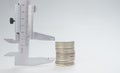 Metal calipers and a stack of silver coins on a gray background Royalty Free Stock Photo