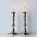 Metal candelabras with wax candles on wooden background.