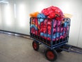 Metal cart for waste collection with a large pile of colorful plastic bags filled with sorted waste ready