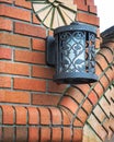 Metal carved lantern on a brick wall. Fragment of the urban landscape