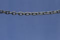 Metal chain hanging against blue sky Royalty Free Stock Photo