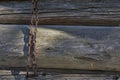 Metal chain hanging on the wall of an old wooden house in a spot of the sun Royalty Free Stock Photo