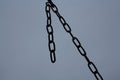 Metal chain of iron links hanging on a grey background dark