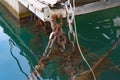 The metal chains on the pier with fishing boats are more rusted from moisture. Close-up of rusty metal fasteners