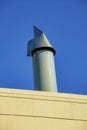 Metal chimney vent or pipe with gray metal in shade with wooden slat foreground beige color and blue and dark sky