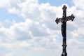 Metal christian cross on blue cloudy sky background, copy space. Catholic church symbol, Jesus Christ Faith, spirituality