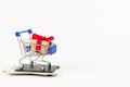 Metal chrome shiny shopping trolley on wheels with gift box on wallet with dollars on white background