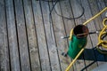 Metal cleat on wooden dock with mooring rope tied to it Royalty Free Stock Photo