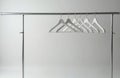 Metal clothes rack holds several white empty hangers on bright studio background. Simple minimalist wardrobe storage setup ready Royalty Free Stock Photo