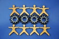 Metal cogs cogwheels and wooden figures of people holding hands Royalty Free Stock Photo