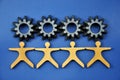 Metal cogs cogwheels and wooden figures of people holding hands Royalty Free Stock Photo