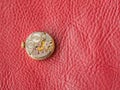 Metal cogwheels inside clock on red leather background. Clockwork