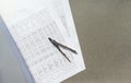 A metal compass lies on papers on which tables with many calculations and numbers are printed. Royalty Free Stock Photo