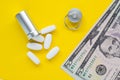 Metal container for pills and money on a yellow background, concept of expensive drugs, close-up Royalty Free Stock Photo