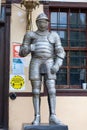 Metal costume of ancient knight near entrance to building. Announcements of need to wear medical mask and maintain distance of 1.5