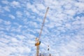 Metal crane is working in a daytime with beautiful blue sky and clouds Royalty Free Stock Photo